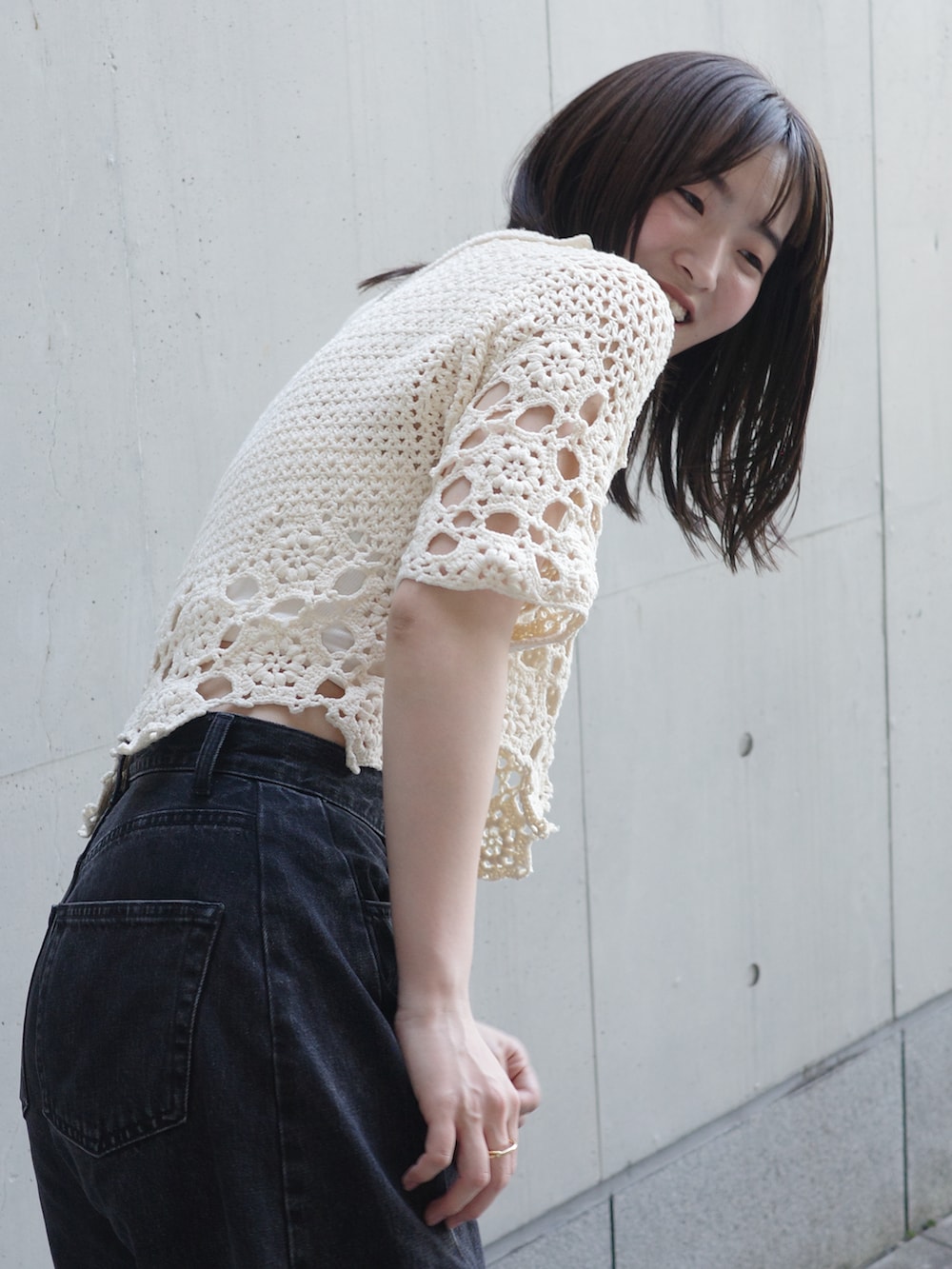 ホワイト系のニット/セーター、ブラック系のデニムパンツ、ホワイト系のスニーカーを着用したレディースの夏コーディネートの3枚目の写真