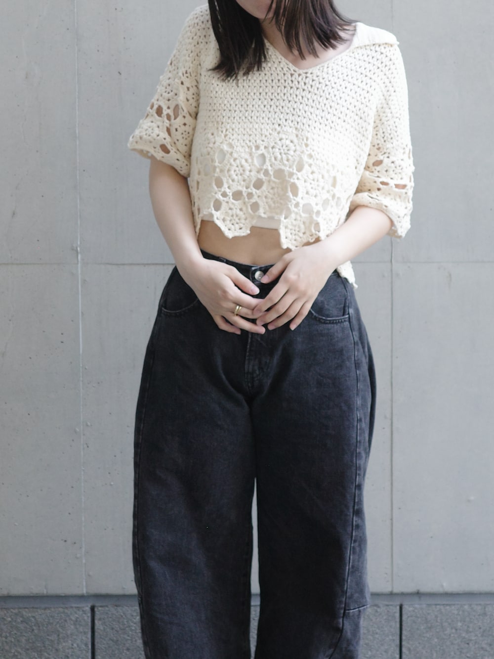 ホワイト系のニット/セーター、ブラック系のデニムパンツ、ホワイト系のスニーカーを着用したレディースの夏コーディネートの2枚目の写真