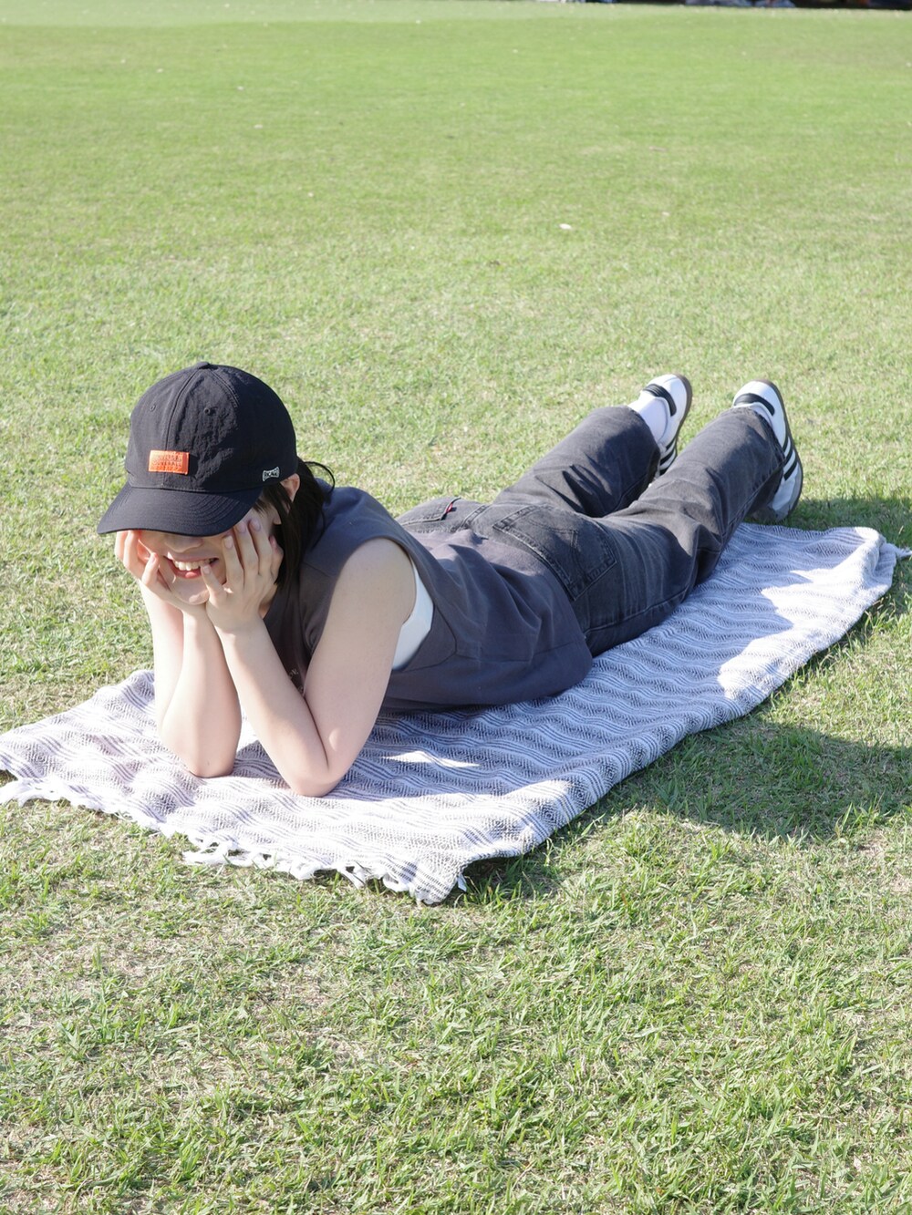 グレー系のTシャツ/カットソー、ブラック系のデニムパンツ、ホワイト系のスニーカーを着用したレディースの春コーディネートの2枚目の写真