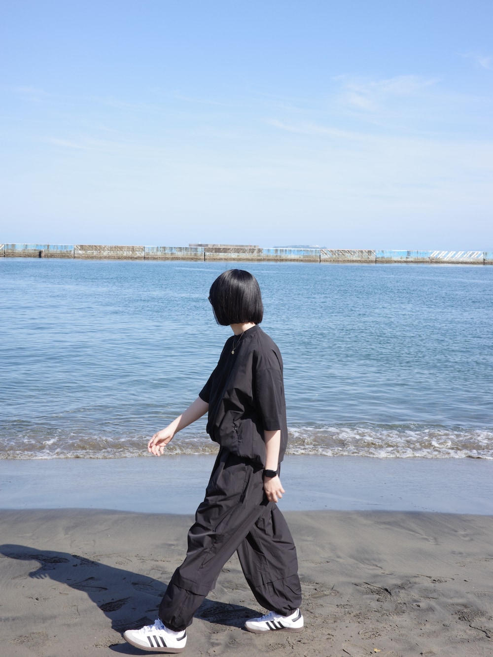 ブラック系のシャツ/ブラウス、ブラック系のその他パンツ、ホワイト系のスニーカーを着用したレディースの春コーディネートの2枚目の写真