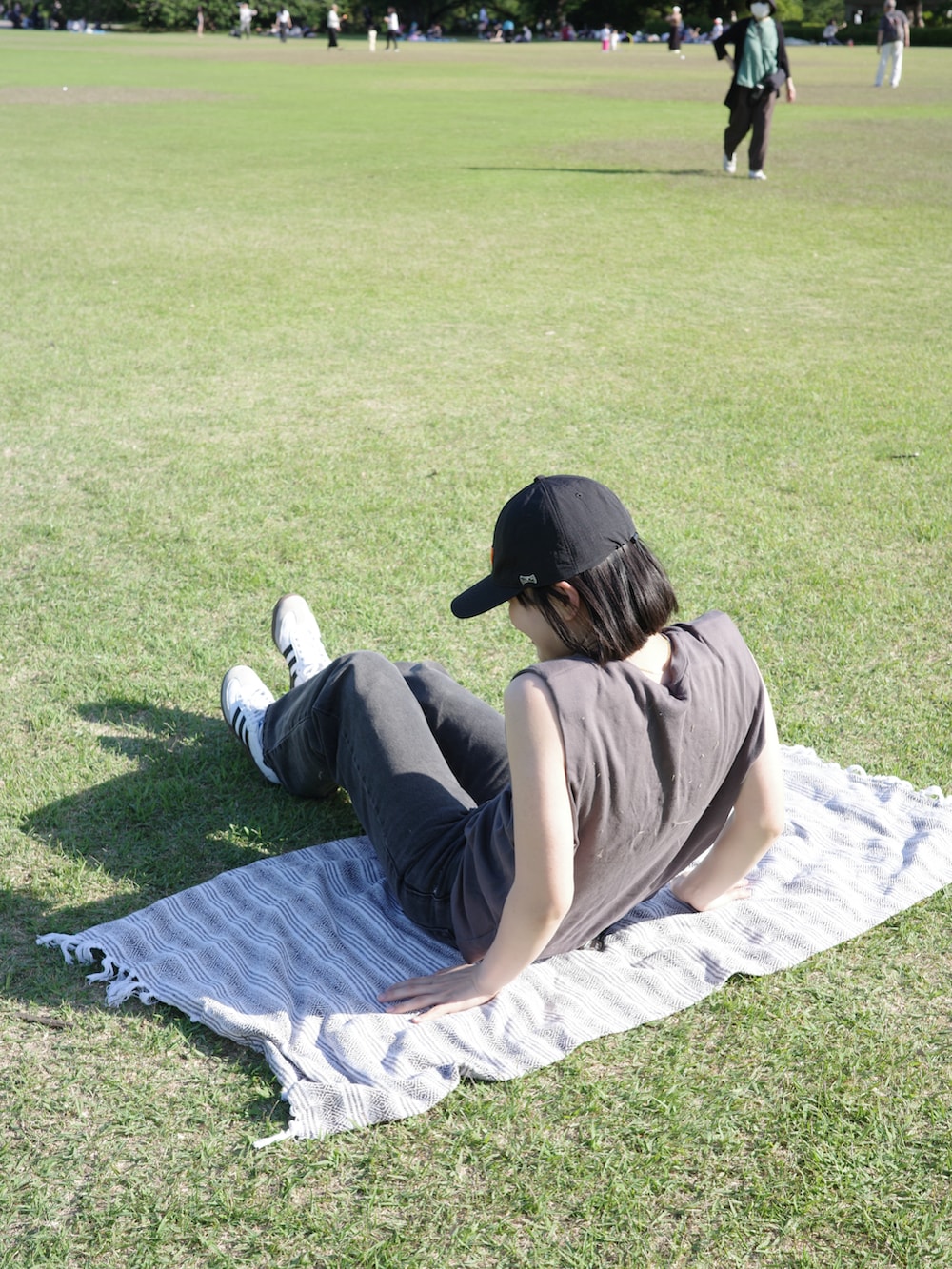 グレー系のTシャツ/カットソー、ブラック系のデニムパンツ、ホワイト系のスニーカーを着用したレディースの春コーディネートの3枚目の写真