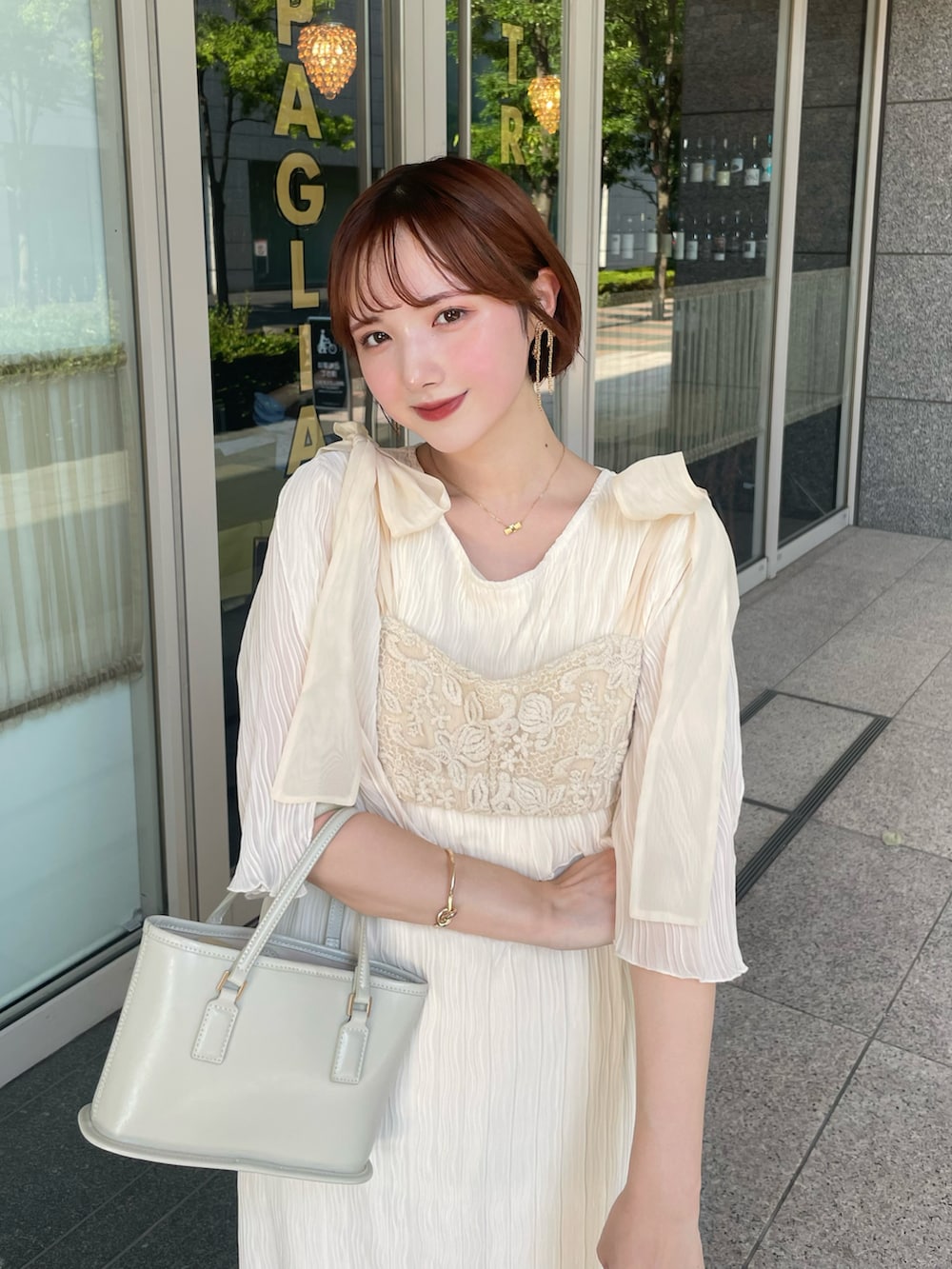 ホワイト系のワンピース、ベージュ系のトップス、ブラウン系のバッグを着用したレディースの夏コーディネートの2枚目の写真