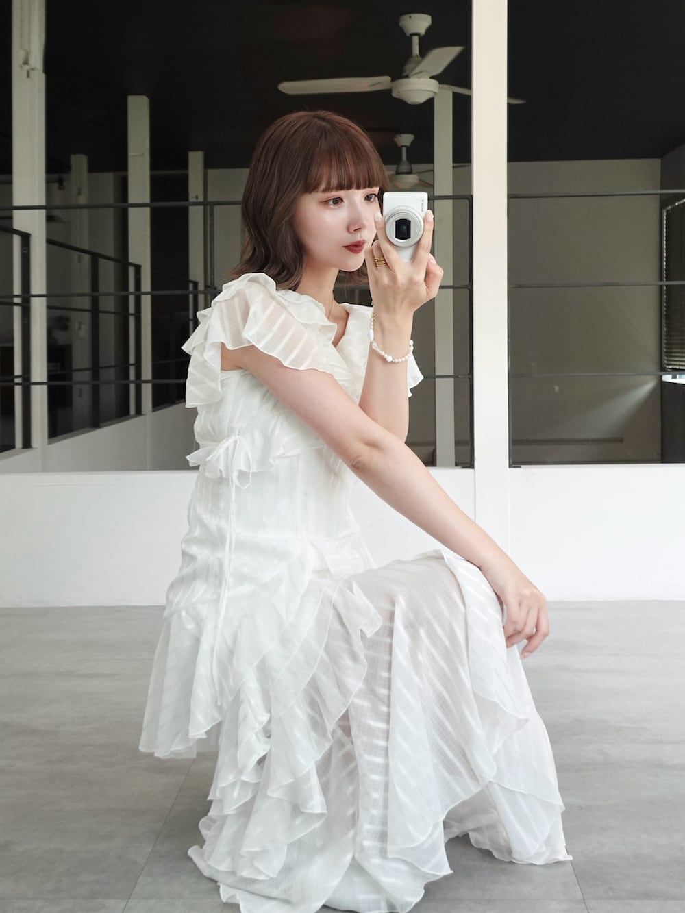 ホワイト系のワンピース、ブラック系のボストンバッグ、ホワイト系のキャミソールを着用したレディースの春コーディネートの2枚目の写真