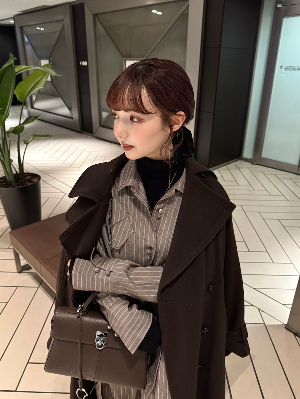 ブラウン系のトレンチコート、ブラウン系のシャツ/ブラウス、ブラック系のニット/セーターを着用したレディースの冬コーディネートの2枚目の写真