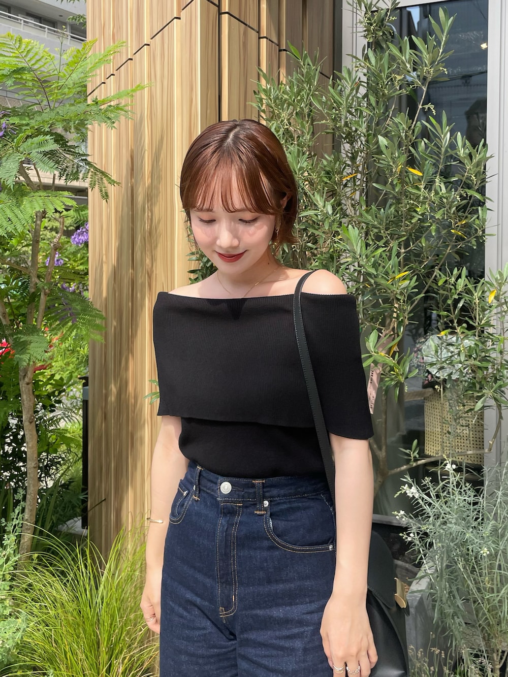 ブルー系のデニムパンツ、ブラック系のニット/セーター、ブラック系のハンドバッグを着用したレディースの夏コーディネートの2枚目の写真