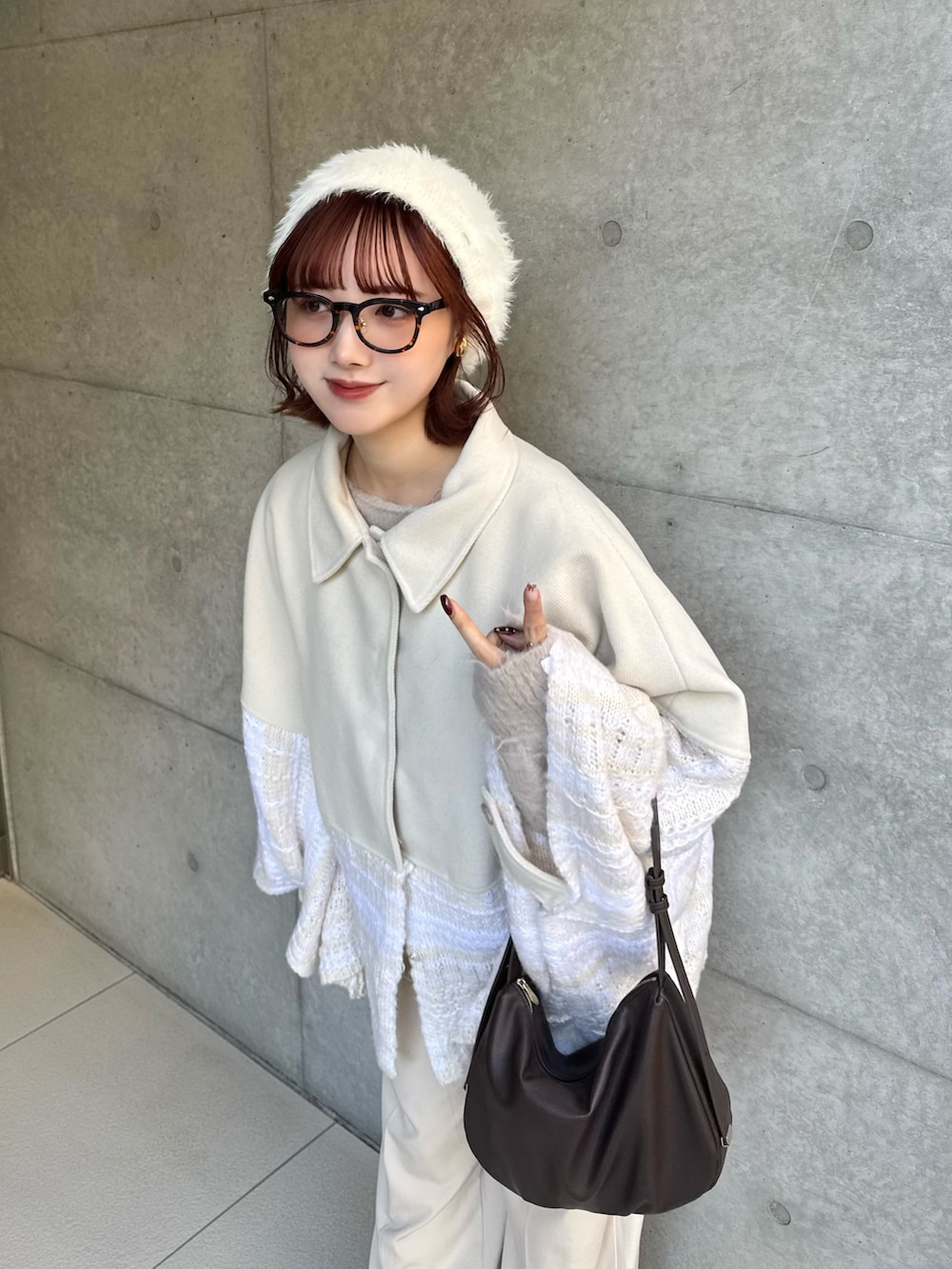 ホワイト系のポンチョ、ベージュ系のニット/セーター、ホワイト系のその他パンツを着用したレディースの冬コーディネートの2枚目の写真