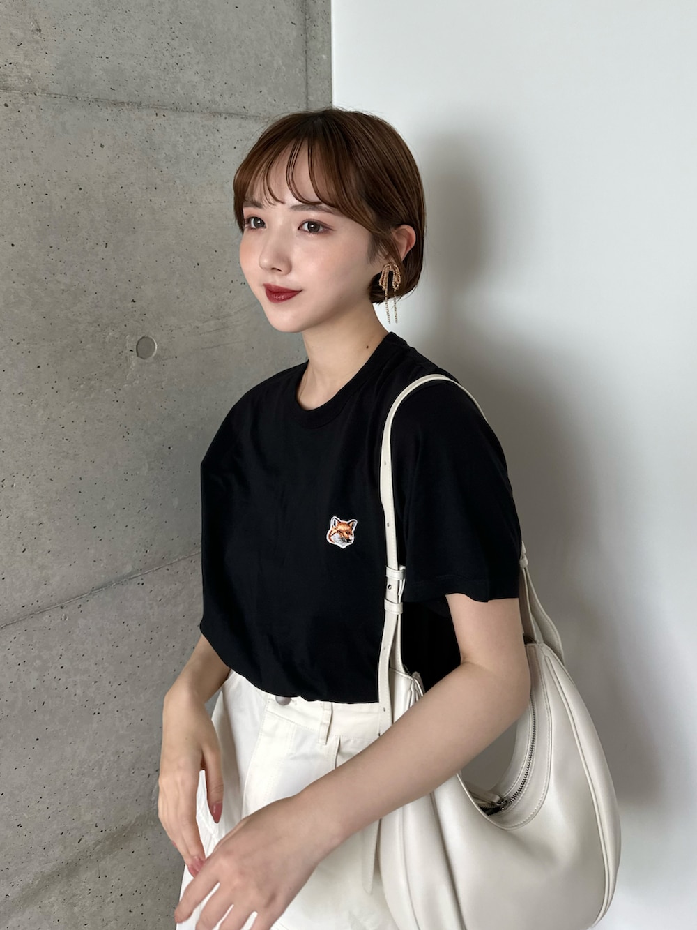 ブラック系のTシャツ/カットソー、ホワイト系のバッグ、ホワイト系のスカートを着用したレディースの春コーディネートの2枚目の写真