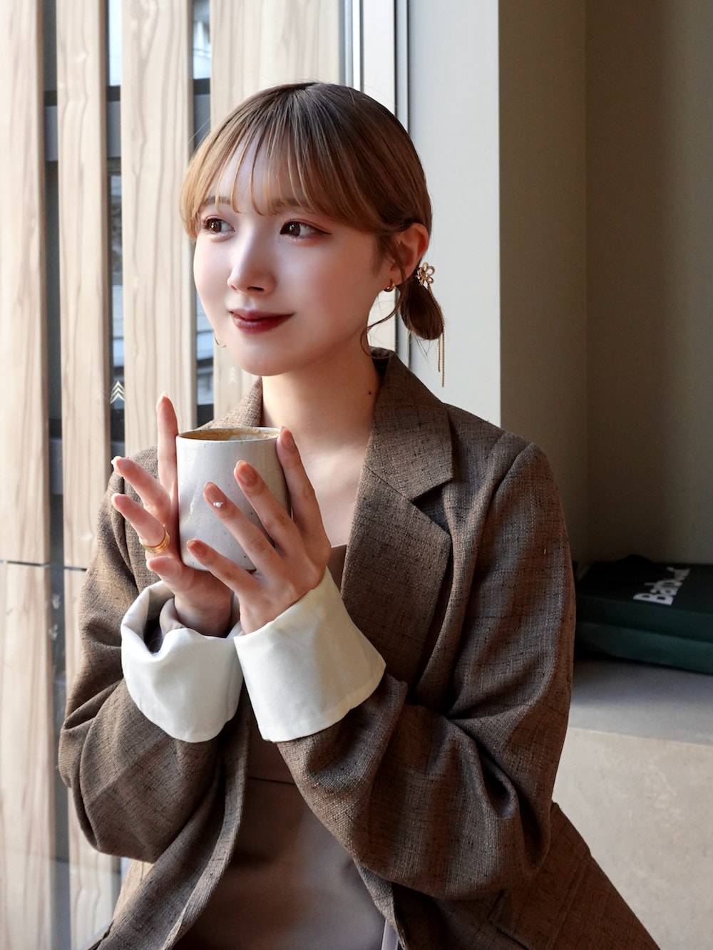 ブラウン系のテーラードジャケット、ブラウン系のバッグ、ブラウン系のローファーを着用したレディースの春コーディネートの2枚目の写真