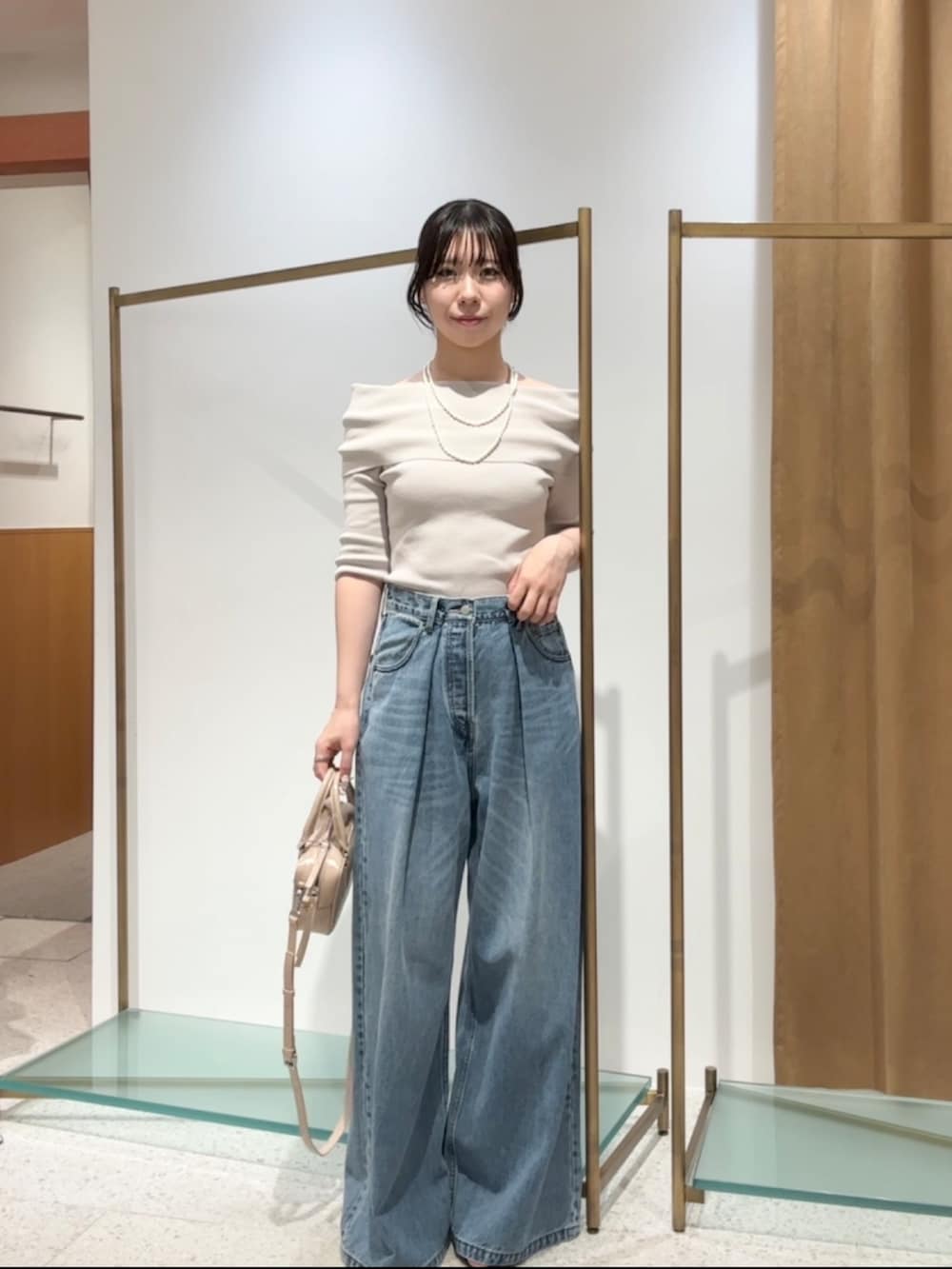 ベージュ系のニット/セーター、ブルー系のデニムパンツ、ベージュ系のハンドバッグを着用したレディースの夏コーディネートの2枚目の写真