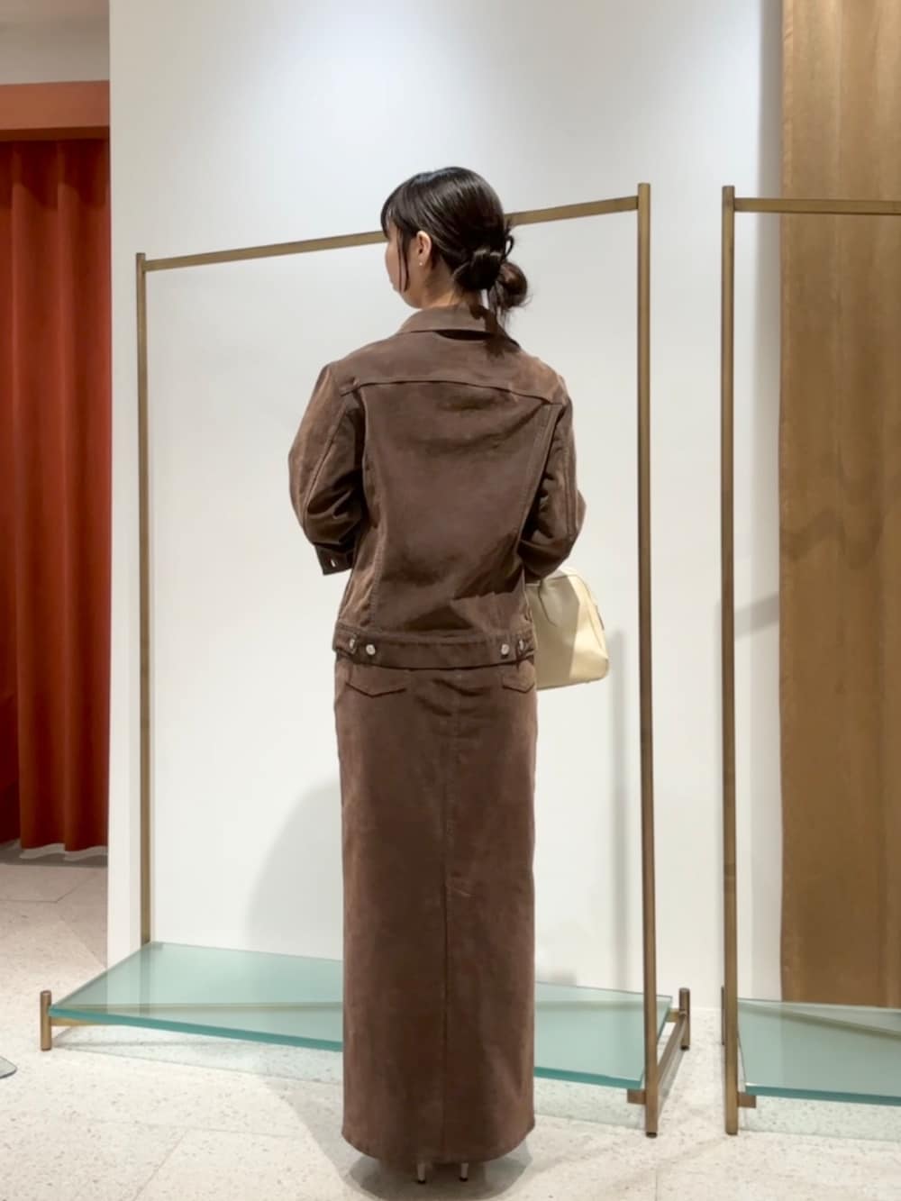 ブラウン系のデニムジャケット、ブラウン系のデニムスカート、ベージュ系のパンプスを着用したレディースの夏コーディネートの3枚目の写真