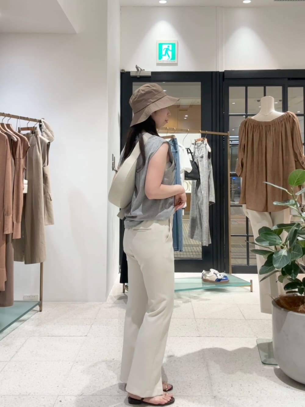 グレー系のTシャツ/カットソー、ホワイト系のスラックス、ホワイト系のボディバッグ/ウエストポーチを着用したレディースの夏コーディネートの2枚目の写真