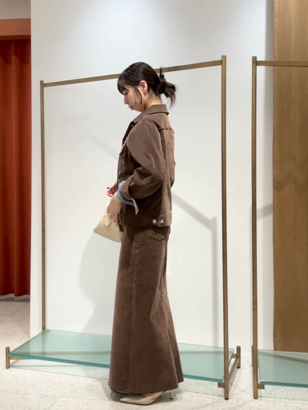 ブラウン系のデニムジャケット、ブラウン系のデニムスカート、ベージュ系のパンプスを着用したレディースの夏コーディネートの4枚目の写真