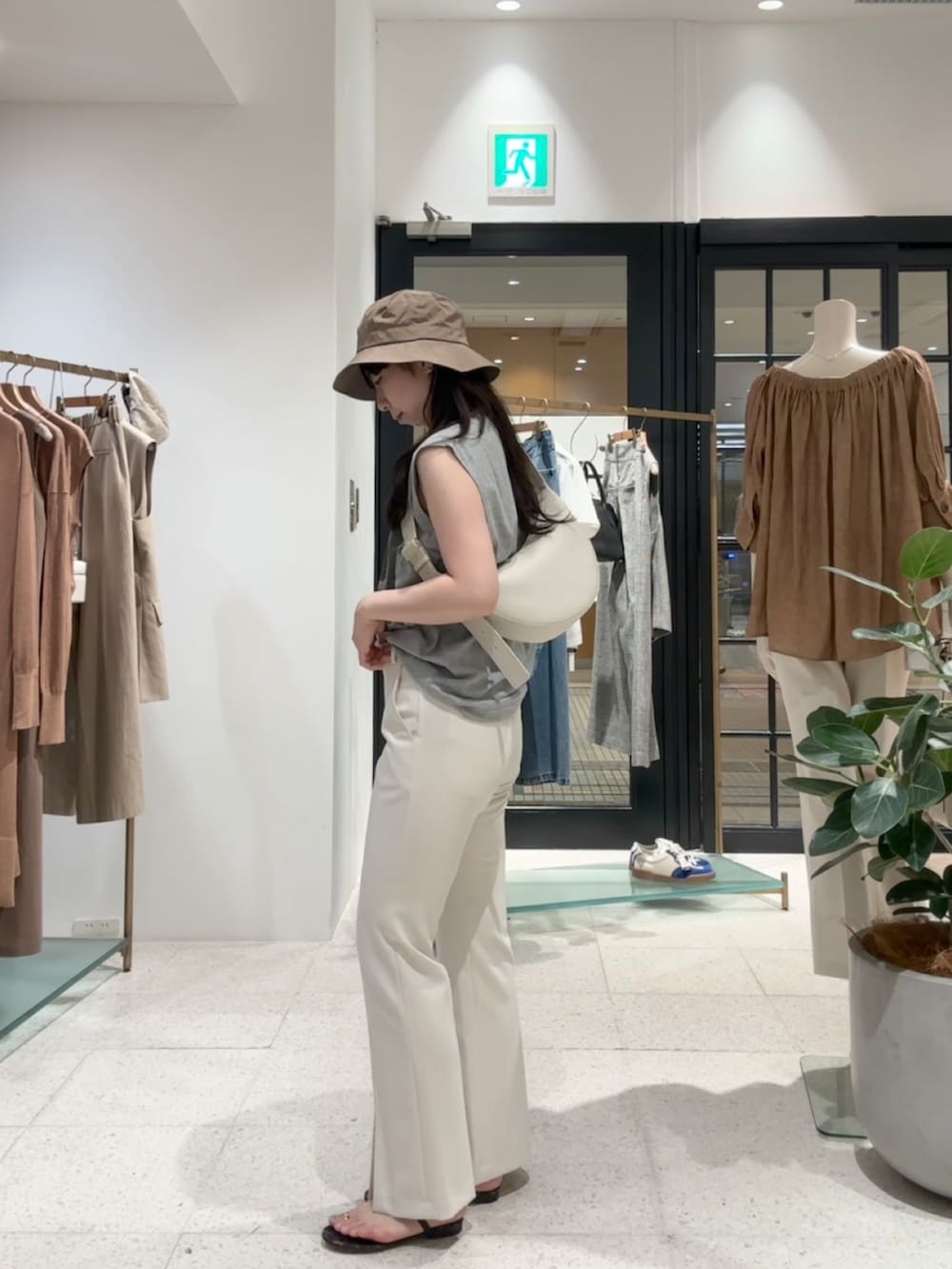 グレー系のTシャツ/カットソー、ホワイト系のスラックス、ホワイト系のボディバッグ/ウエストポーチを着用したレディースの夏コーディネートの4枚目の写真