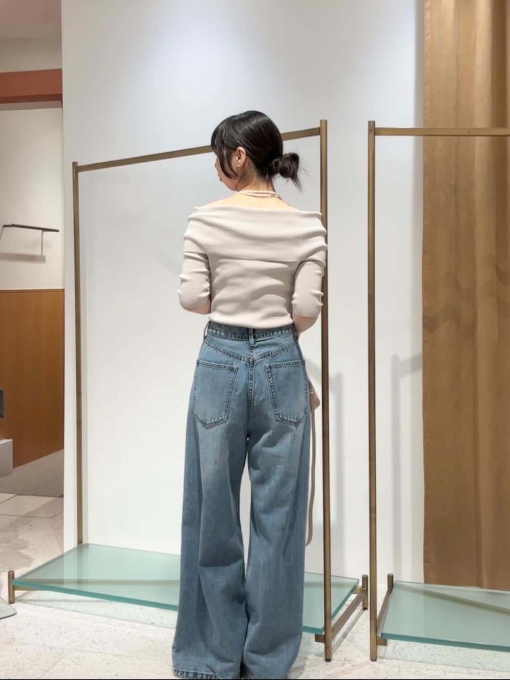 ベージュ系のニット/セーター、ブルー系のデニムパンツ、ベージュ系のハンドバッグを着用したレディースの夏コーディネートの4枚目の写真