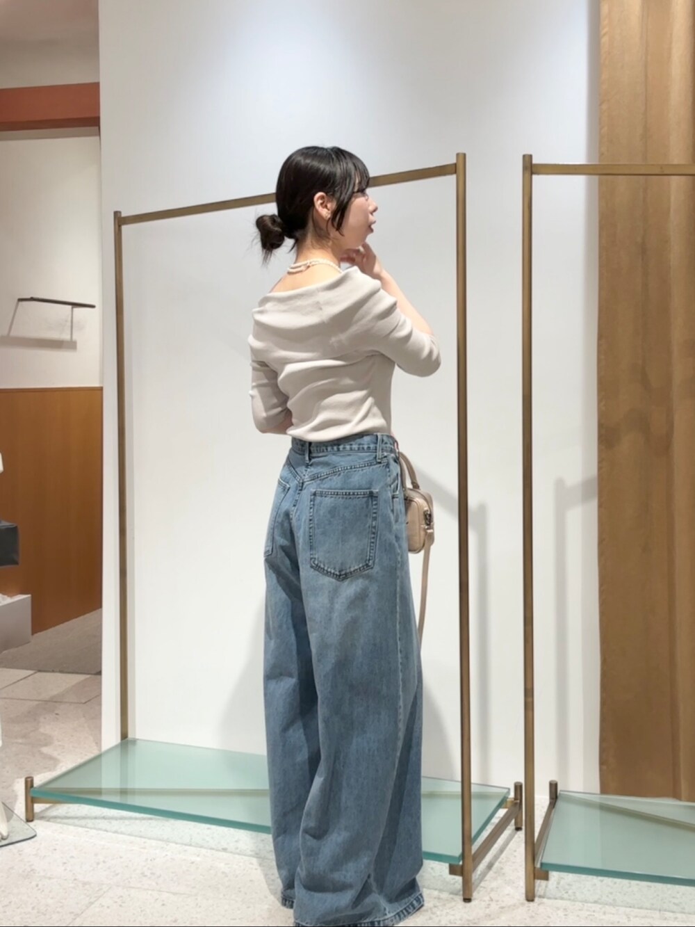 ベージュ系のニット/セーター、ブルー系のデニムパンツ、ベージュ系のハンドバッグを着用したレディースの夏コーディネートの3枚目の写真