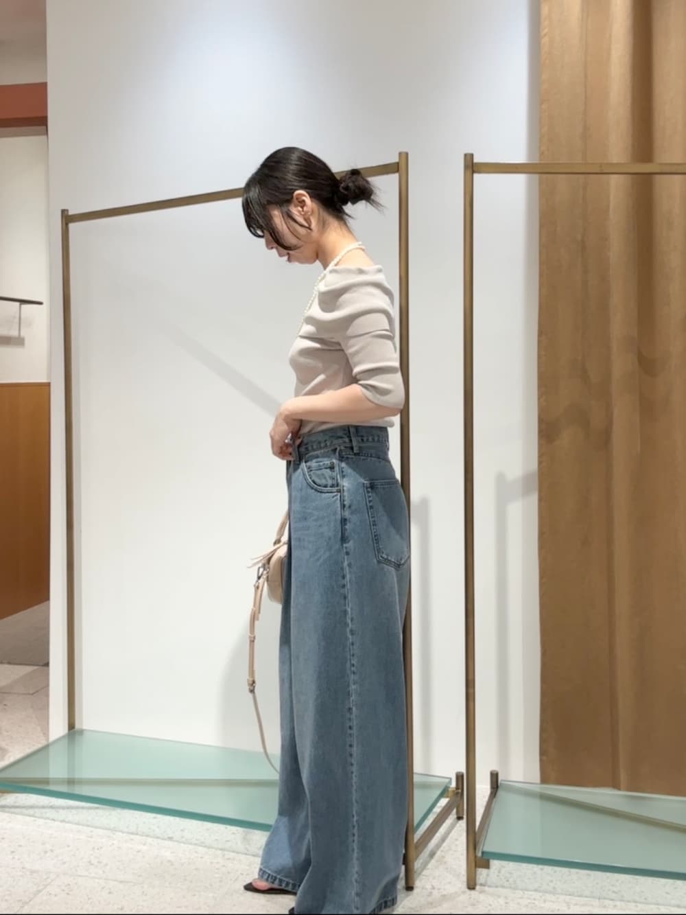 ベージュ系のニット/セーター、ブルー系のデニムパンツ、ベージュ系のハンドバッグを着用したレディースの夏コーディネートの5枚目の写真