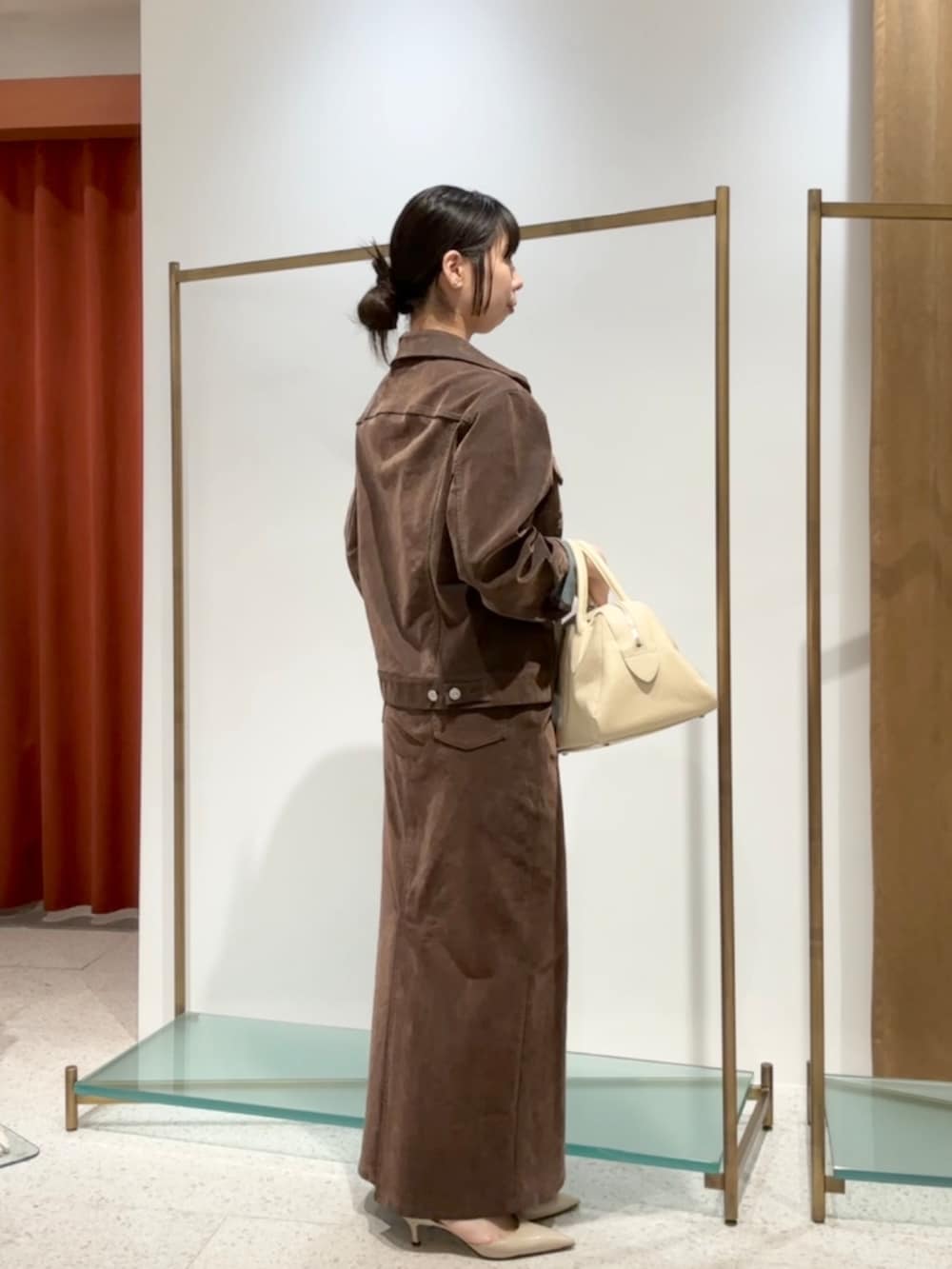 ブラウン系のデニムジャケット、ブラウン系のデニムスカート、ベージュ系のパンプスを着用したレディースの夏コーディネートの2枚目の写真