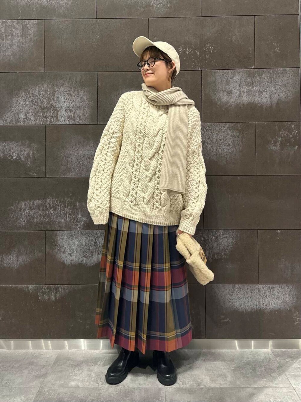 ホワイト系のニット/セーター、ブラック系のブーツ、ブルー系のスカートを着用したレディースの秋コーディネートの2枚目の写真