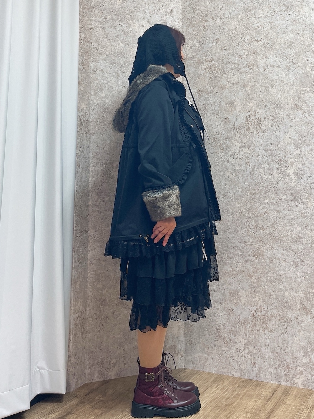 レッド系のブーツ、ブラック系のワンピース、ブラック系のモッズコートを着用したレディースの秋コーディネートの2枚目の写真