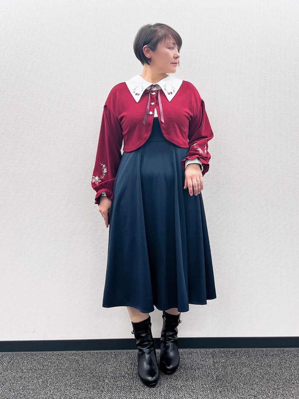 ブルー系のワンピース、レッド系のカーディガン/ボレロ、ブラック系のブーツを着用したレディースの冬コーディネートの2枚目の写真