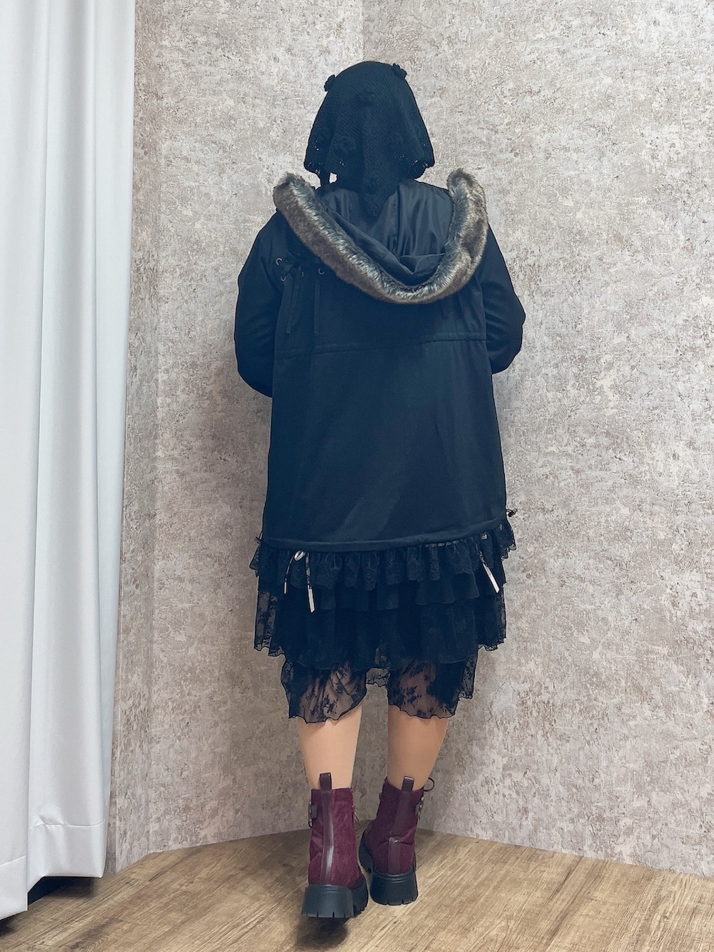 レッド系のブーツ、ブラック系のワンピース、ブラック系のモッズコートを着用したレディースの秋コーディネートの3枚目の写真