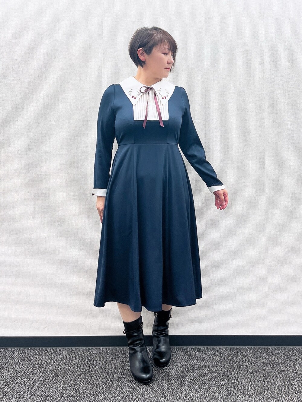 ブルー系のワンピース、レッド系のカーディガン/ボレロ、ブラック系のブーツを着用したレディースの冬コーディネートの5枚目の写真