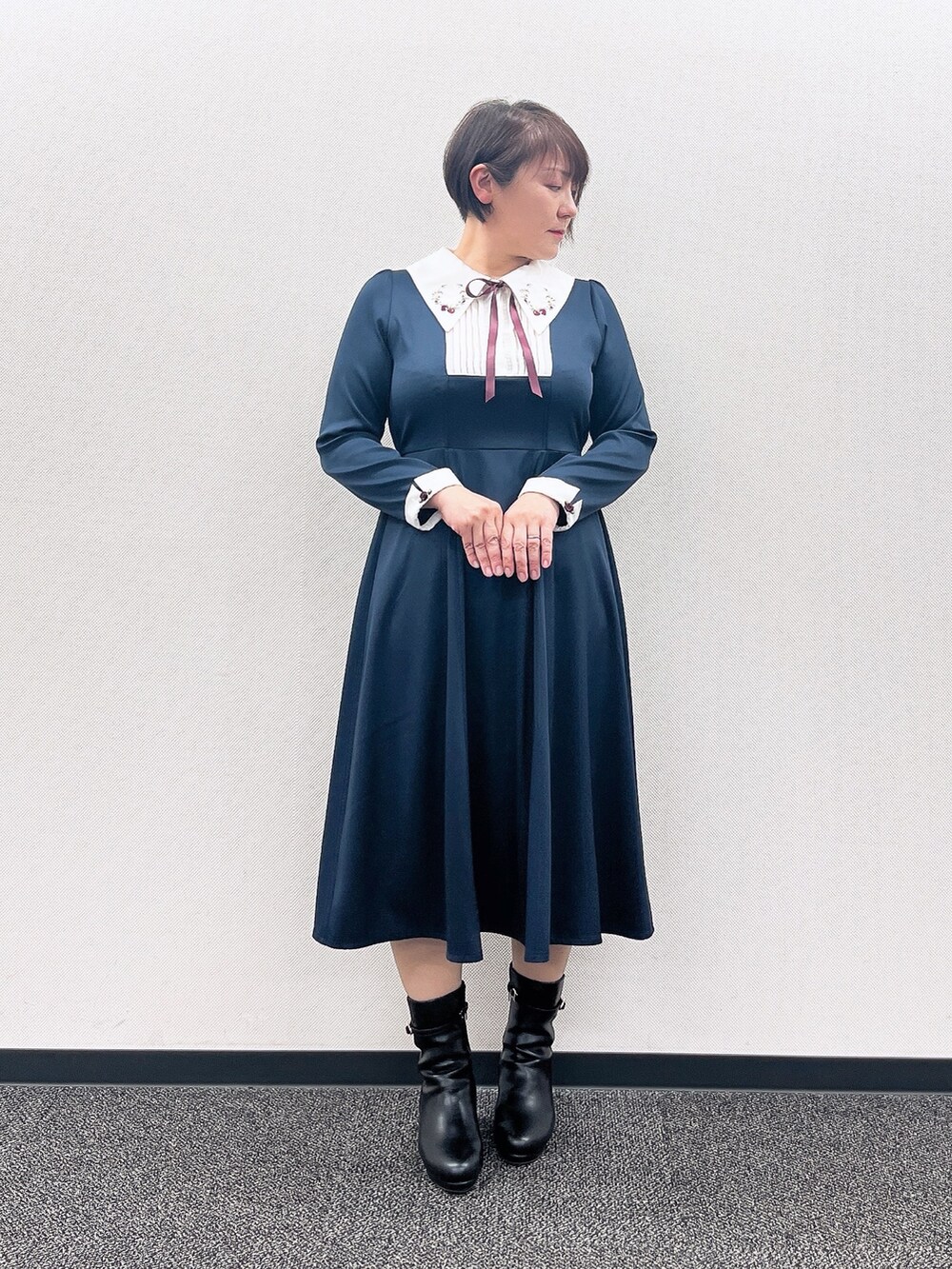 ブルー系のワンピース、レッド系のカーディガン/ボレロ、ブラック系のブーツを着用したレディースの冬コーディネートの4枚目の写真