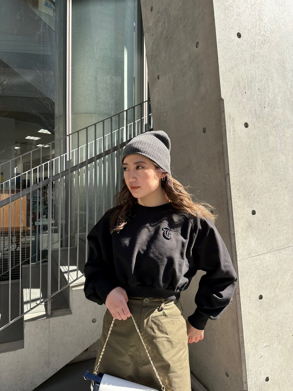 ブラック系のスウェット、ブラック系のブーツ、ブルー系のショルダーバッグを着用したレディースの冬コーディネートの3枚目の写真