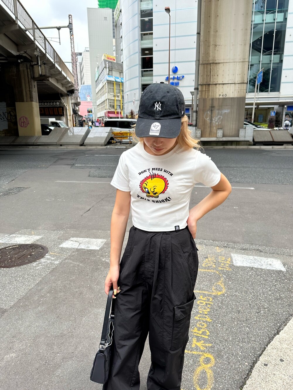 ブラック系のカーゴパンツ、ホワイト系のTシャツ/カットソー、ブラック系のハンドバッグを着用したレディースの夏コーディネートの4枚目の写真