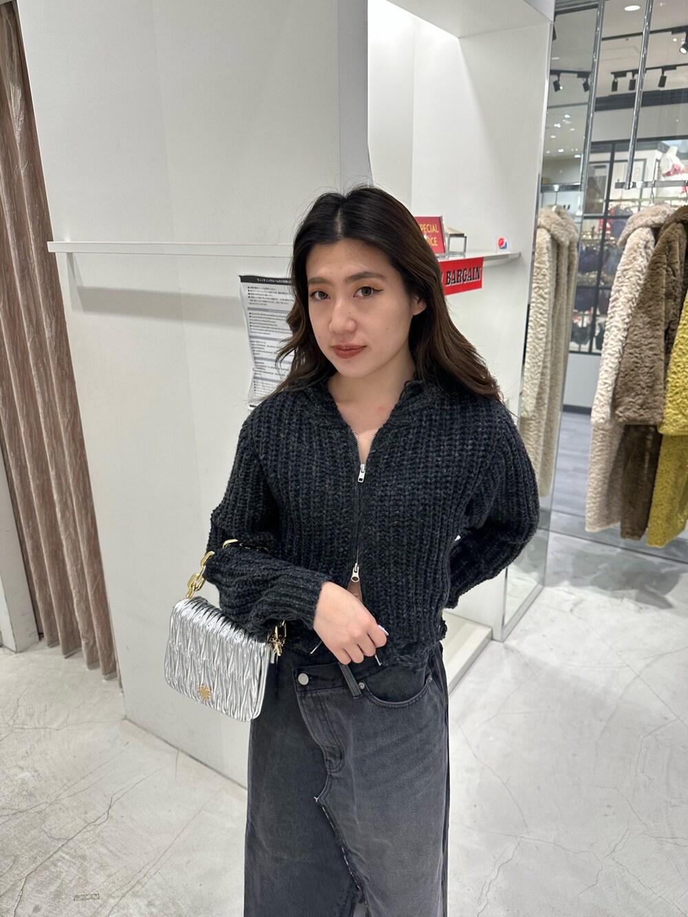 ブラック系のデニムスカート、ブラック系のニット/セーター、ブラック系のブーツを着用したレディースの冬コーディネートの4枚目の写真