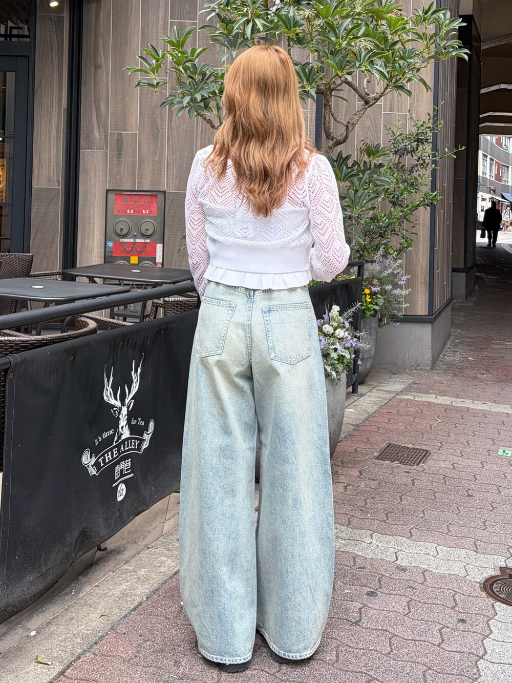 ブルー系のデニムパンツ、ホワイト系のカーディガン/ボレロを着用したレディースの春コーディネートの3枚目の写真