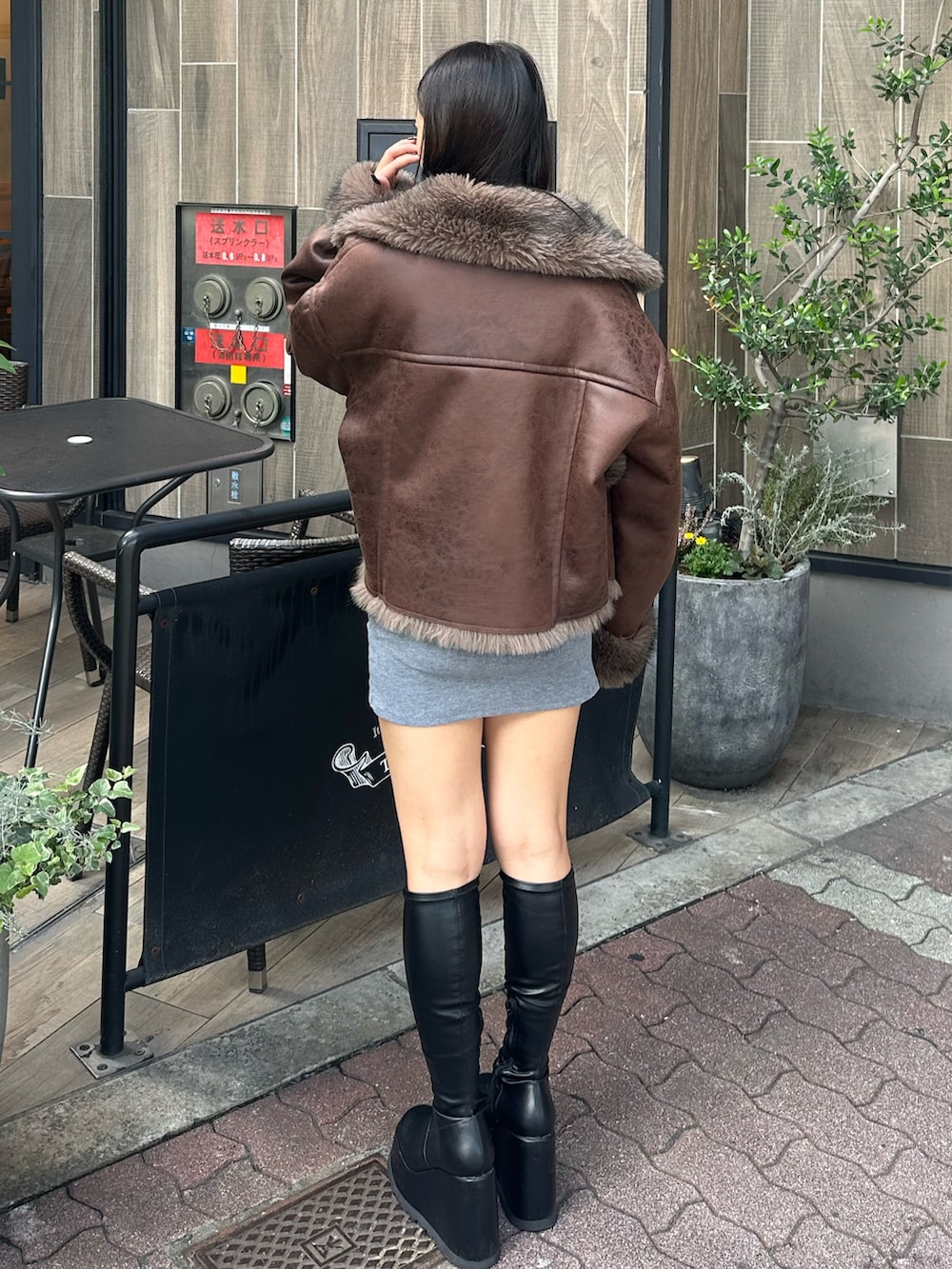 グレー系のワンピース、ブラウン系のブルゾン、ブラック系のブーツを着用したレディースの秋コーディネートの3枚目の写真
