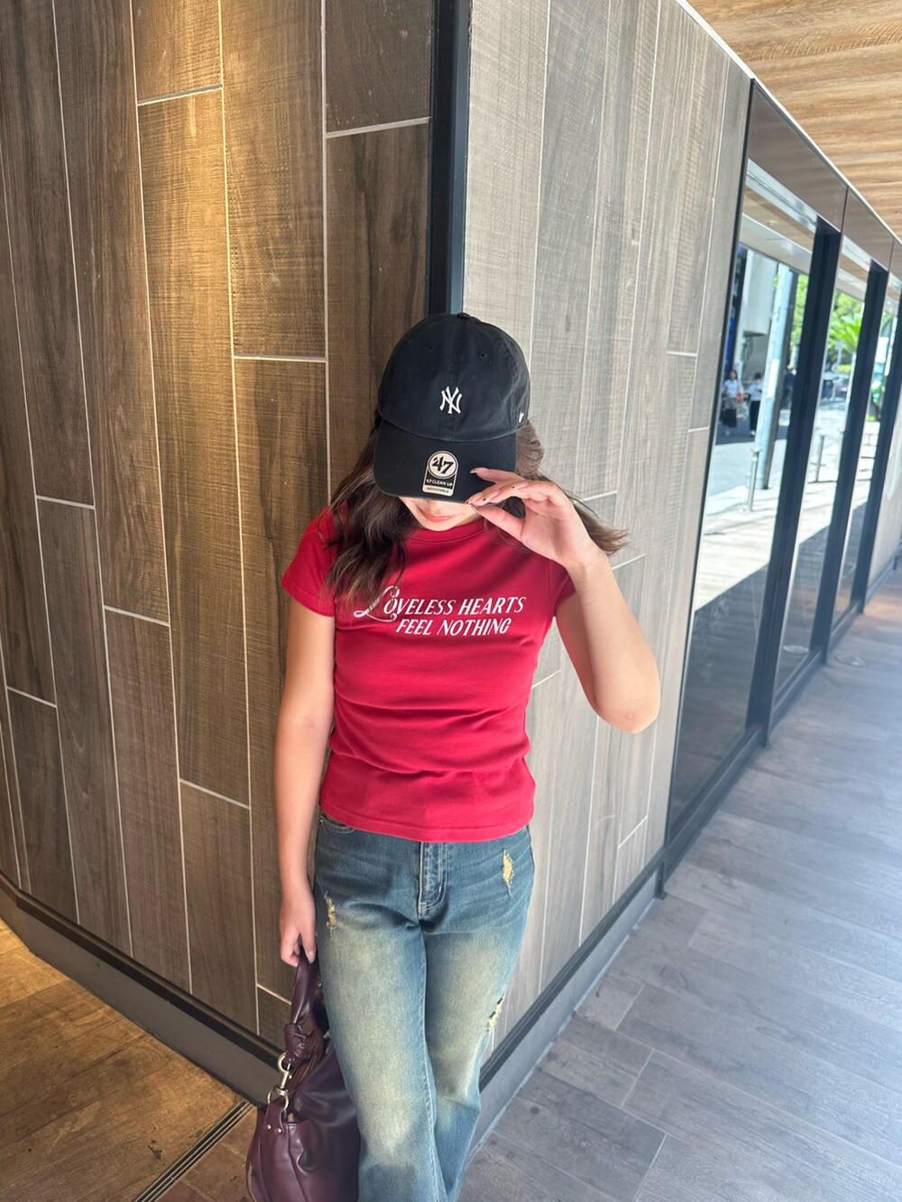 ブルー系のデニムパンツ、レッド系のハンドバッグ、ブラック系のブーツを着用したレディースの秋コーディネートの4枚目の写真