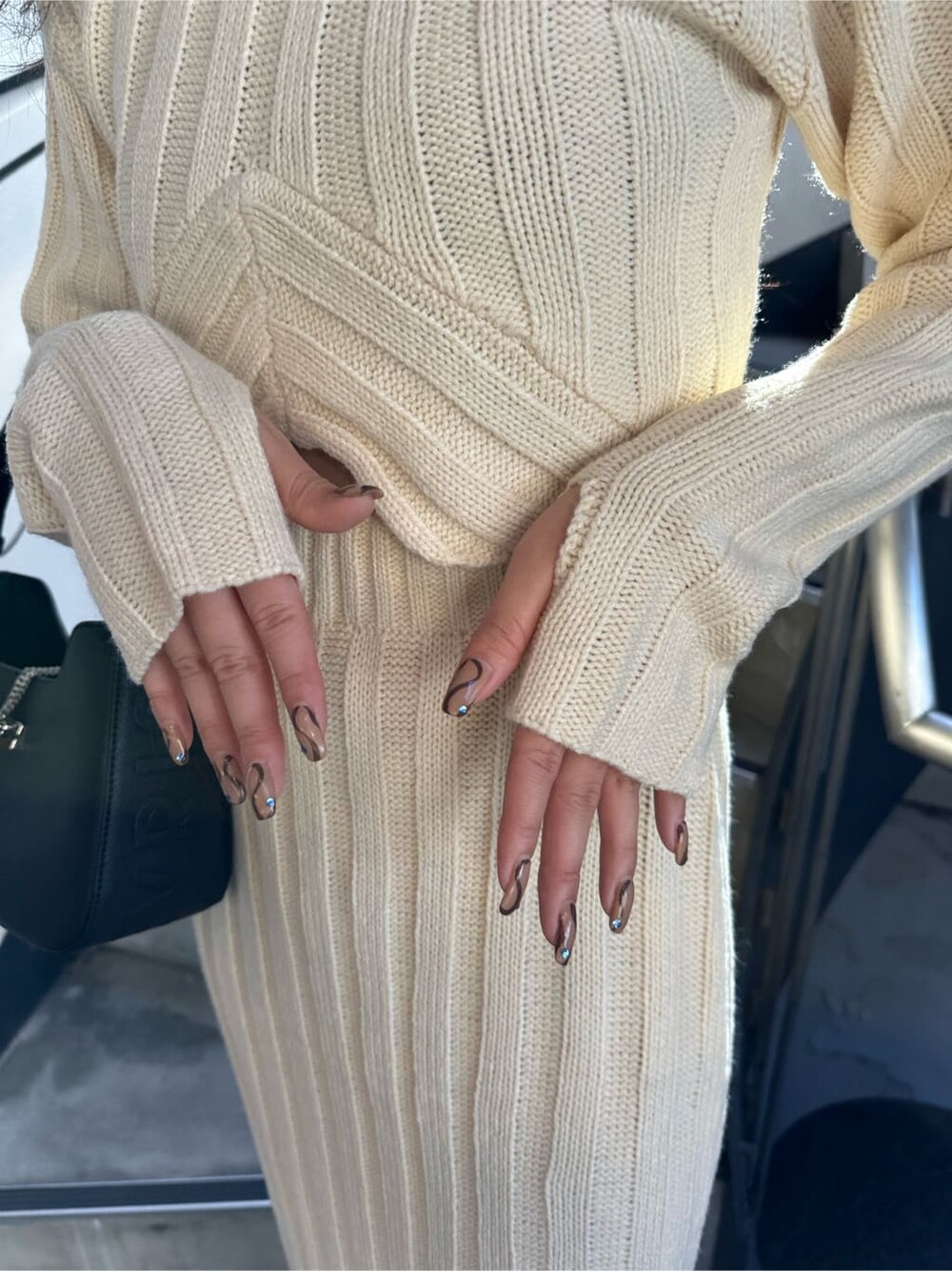 ホワイト系のスカート、ホワイト系のニット/セーター、ブラック系のハンドバッグを着用したレディースの秋コーディネートの4枚目の写真