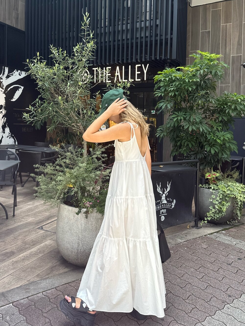 ホワイト系のワンピース、ブラック系のハンドバッグ、ブラック系のサンダルを着用したレディースの夏コーディネートの2枚目の写真