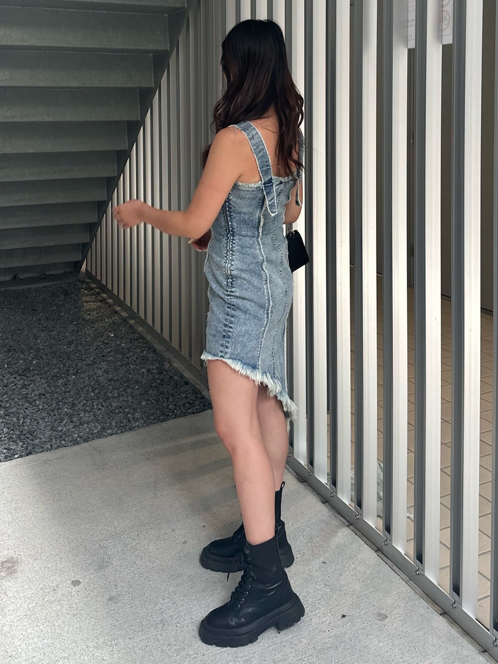 ブラック系のショルダーバッグ、ブラック系のブーツ、ブルー系のワンピースを着用したレディースの夏コーディネートの3枚目の写真