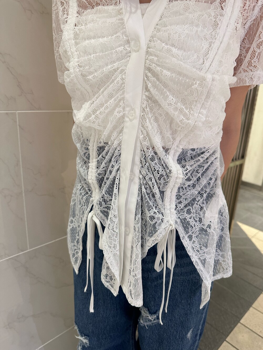 ホワイト系のシャツ/ブラウス、ブルー系のデニムパンツ、ブラック系のサンダルを着用したレディースの春コーディネートの5枚目の写真