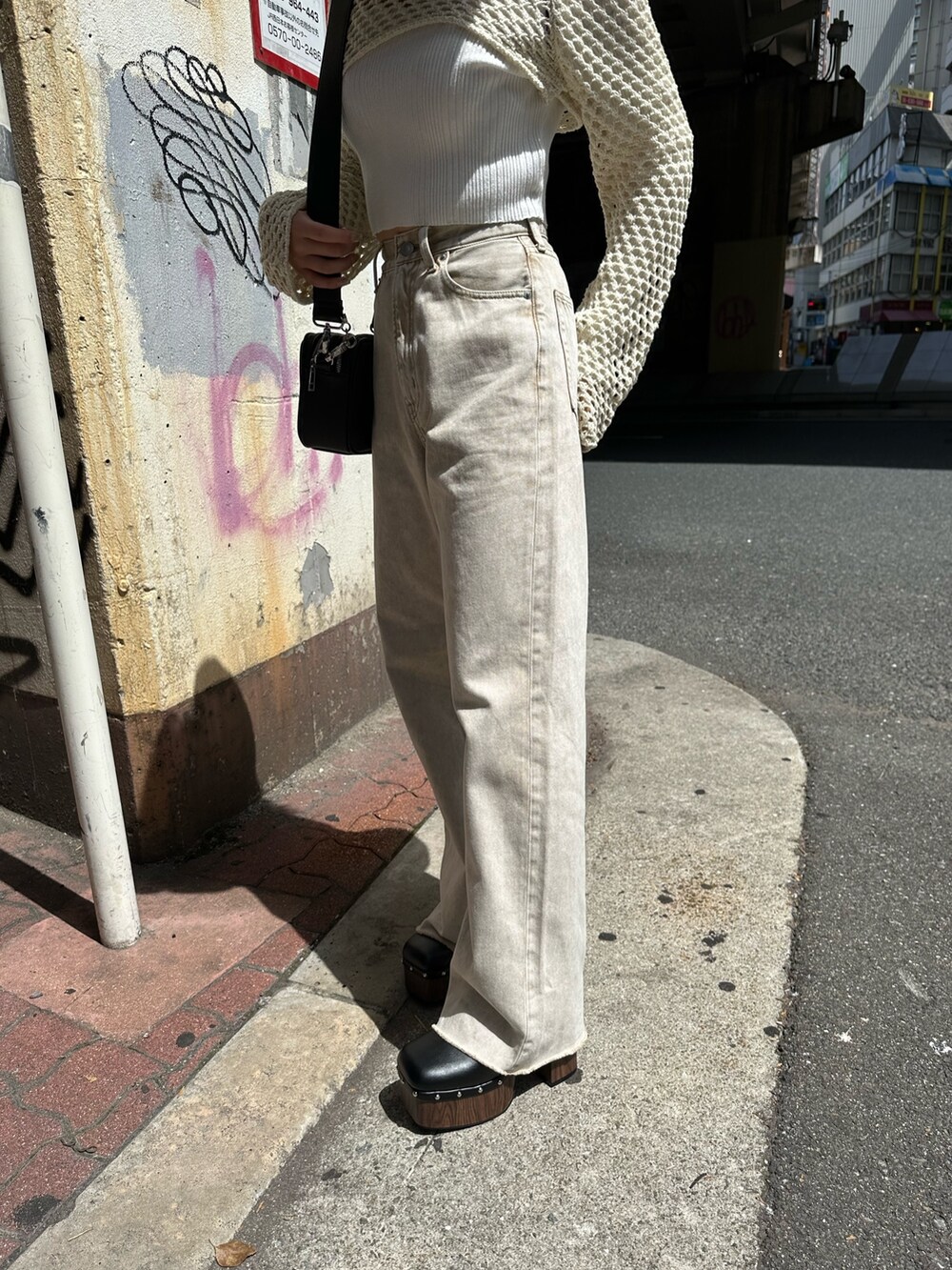 ベージュ系のデニムパンツ、ブラック系のサンダル、ホワイト系のニット/セーターを着用したレディースの春コーディネートの6枚目の写真