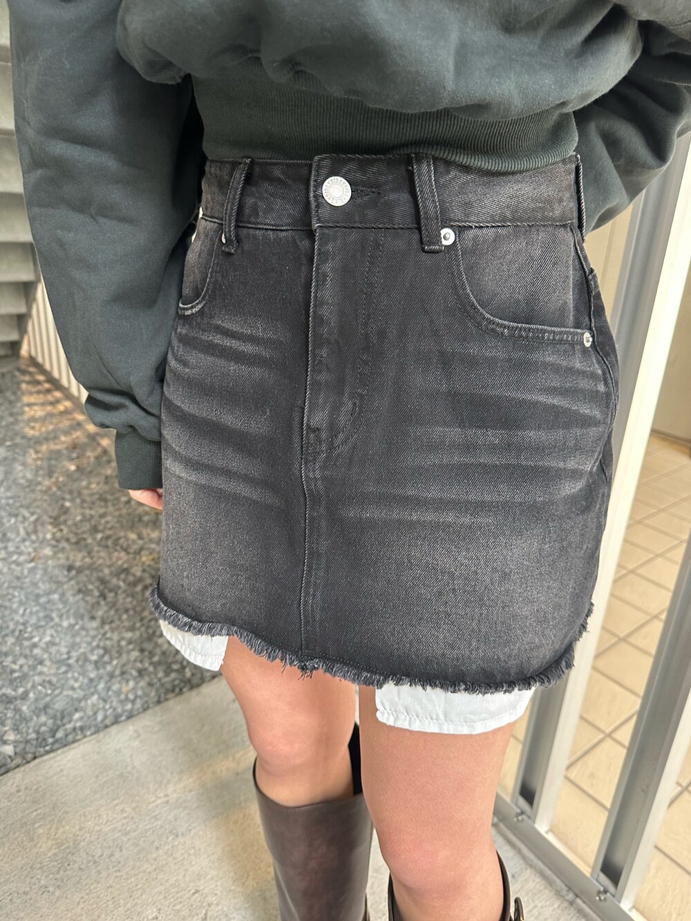 ブラック系のデニムスカート、ブラウン系のブーツ、ブラック系のスウェットを着用したレディースの冬コーディネートの6枚目の写真