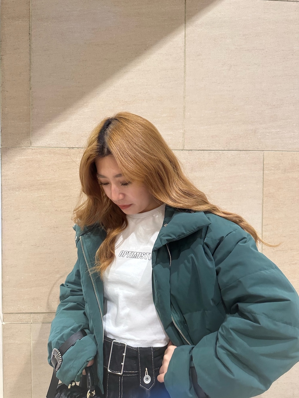 ブルー系のデニムスカート、ホワイト系のTシャツ/カットソー、グリーン系のダウンジャケット/コートを着用したレディースの秋コーディネートの3枚目の写真