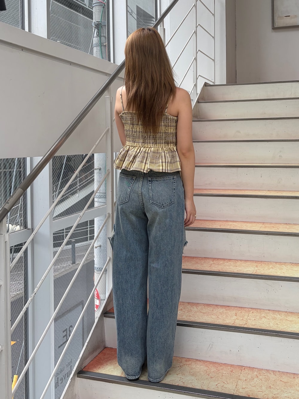 イエロー系のキャミソール、ブルー系のデニムパンツ、ブラック系のブーツを着用したレディースの夏コーディネートの3枚目の写真