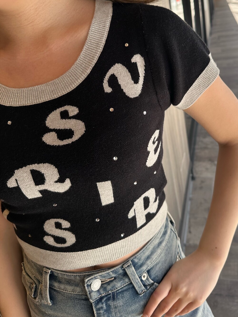 ブラック系のニット/セーター、ブルー系のデニムパンツ、その他のサンダルを着用したレディースの春コーディネートの6枚目の写真