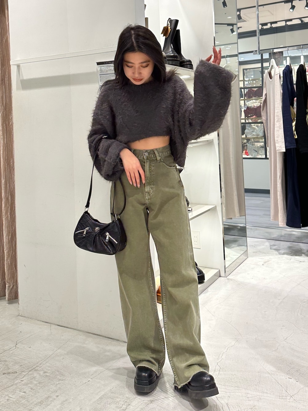 グリーン系のデニムパンツ、グレー系のニット/セーター、ブラック系のショルダーバッグを着用したレディースの冬コーディネートの2枚目の写真