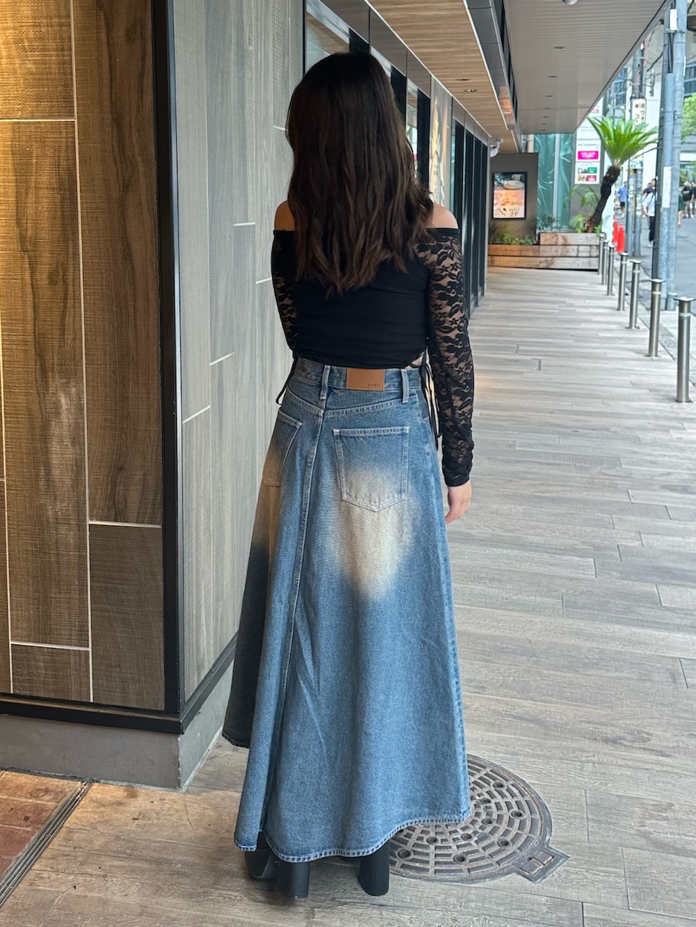 ブルー系のデニムスカート、ブラック系のTシャツ/カットソー、ブラック系のブーツを着用したレディースの秋コーディネートの3枚目の写真