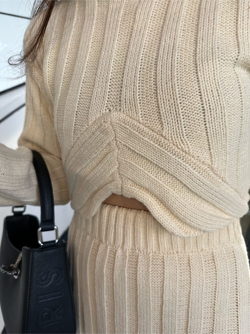 ホワイト系のスカート、ホワイト系のニット/セーター、ブラック系のハンドバッグを着用したレディースの秋コーディネートの5枚目の写真