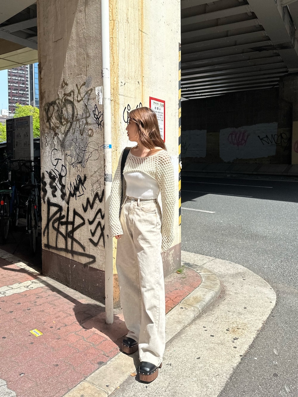 ベージュ系のデニムパンツ、ブラック系のサンダル、ホワイト系のニット/セーターを着用したレディースの春コーディネートの2枚目の写真