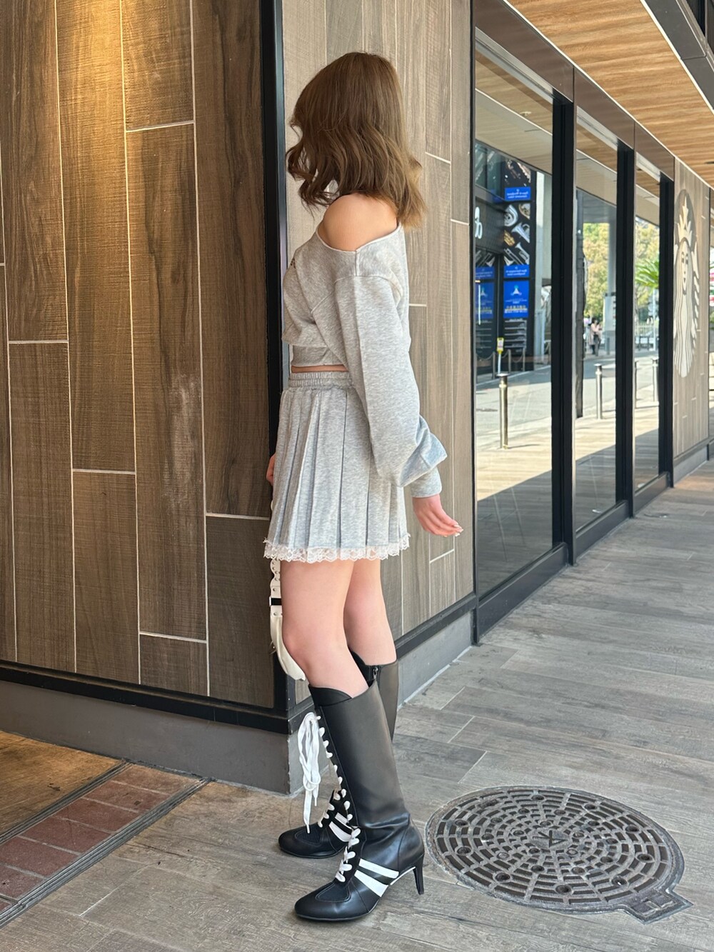 ホワイト系のショルダーバッグ、ブラック系のブーツ、グレー系のスウェットを着用したレディースの春コーディネートの2枚目の写真