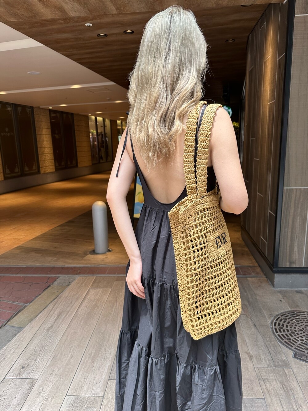 ブラック系のワンピース、ブラック系のサンダル、ベージュ系のトートバッグを着用したレディースの夏コーディネートの5枚目の写真