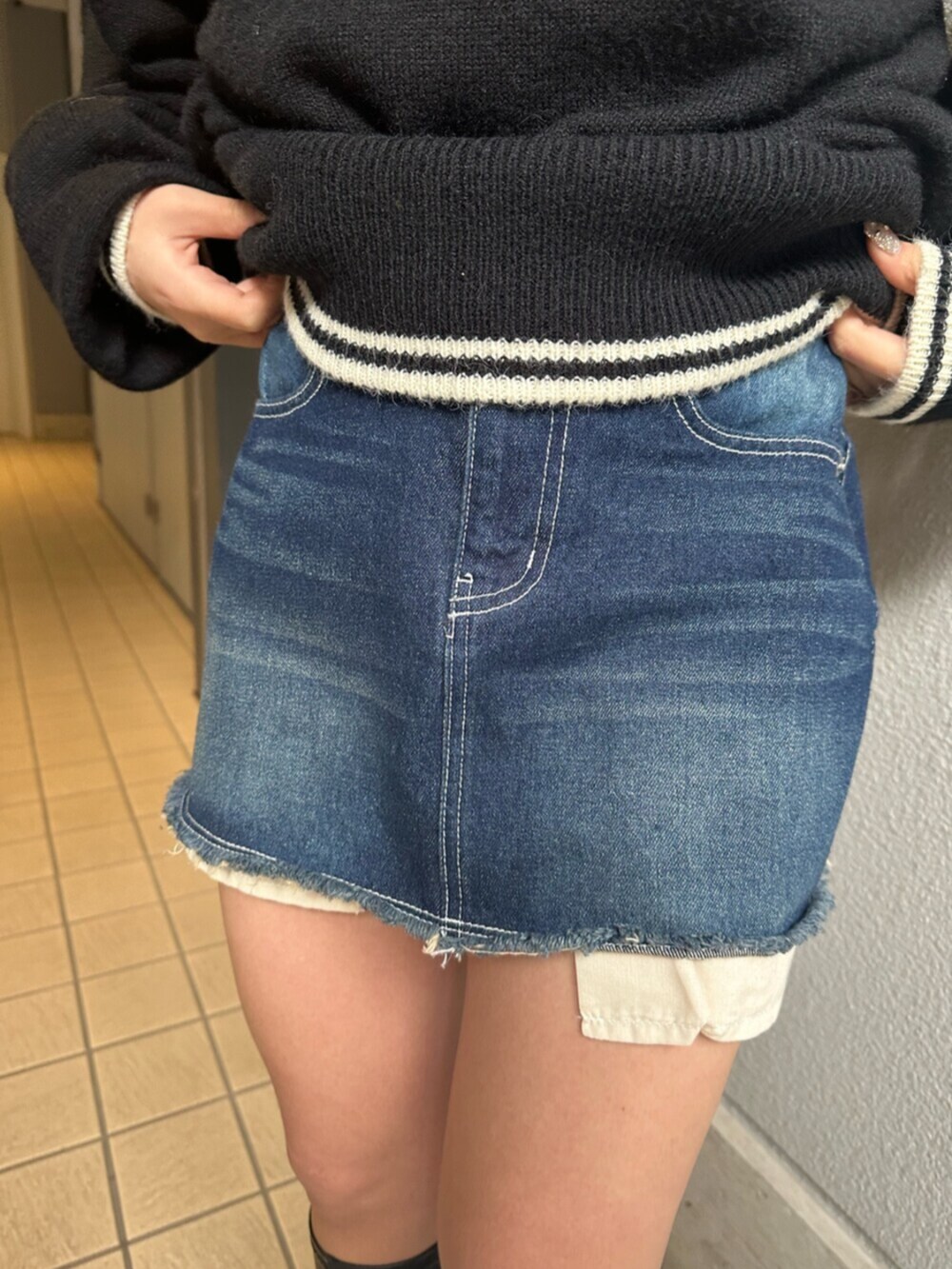 ブラック系のブーツ、ブルー系のデニムスカート、ブラック系のニット/セーターを着用したレディースの冬コーディネートの8枚目の写真