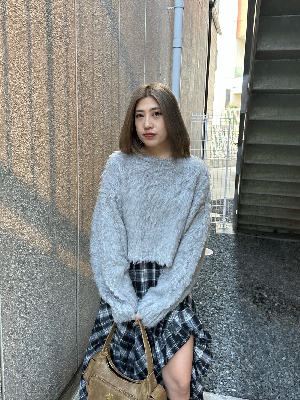 グレー系のニット/セーター、ブラック系のスカート、ブラック系のブーツを着用したレディースの冬コーディネートの5枚目の写真